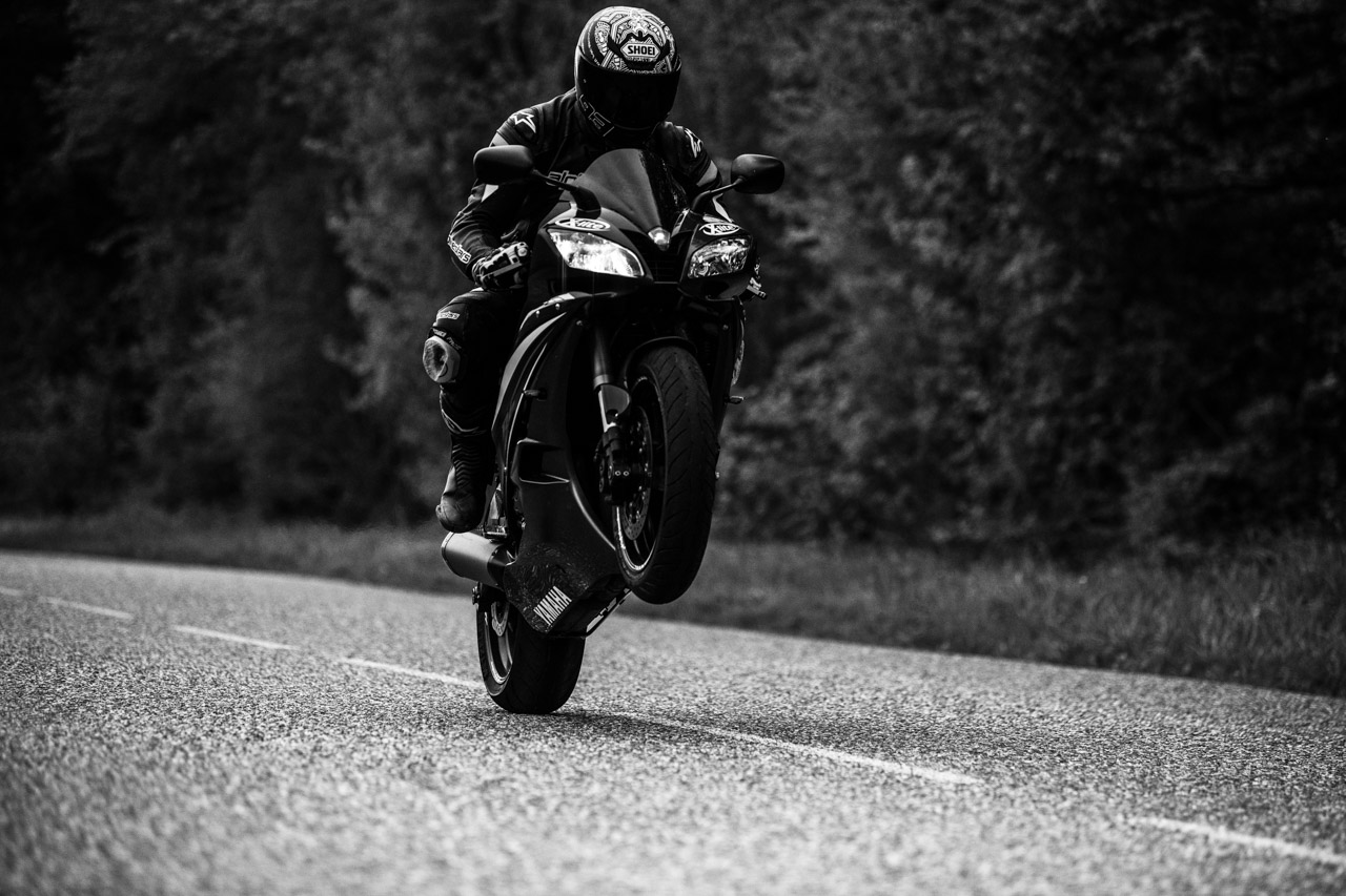 Motorradfahrer auf einer Waldstraße in Schwarz-Weiß