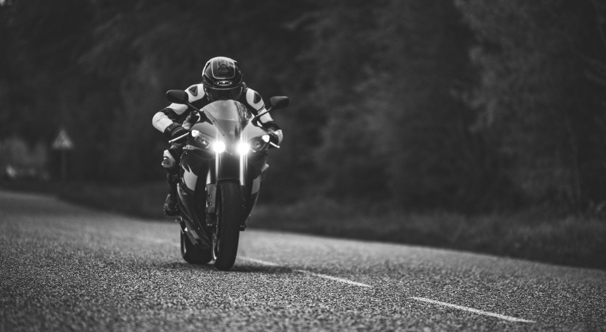 Motorrad mit eingeschalteten Scheinwerfern in Schwarz-Weiß